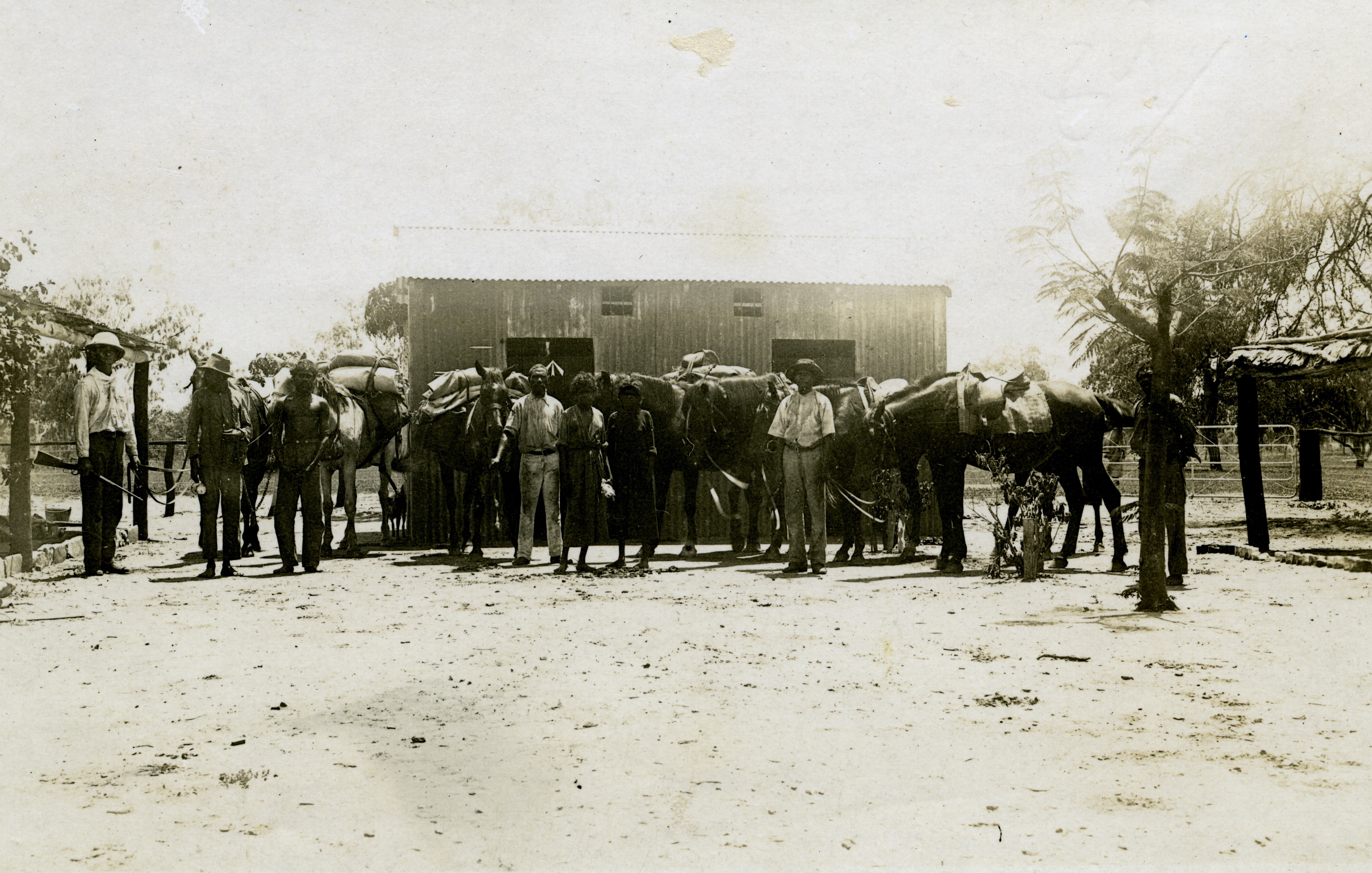 Lock-up at Police Station, Leichhardt's Bar, NT. Mounted Constable John Robert Johns is on the left. The third person from the left is Neighbour. He is a prisoner in chains which are held by the man second from the left.